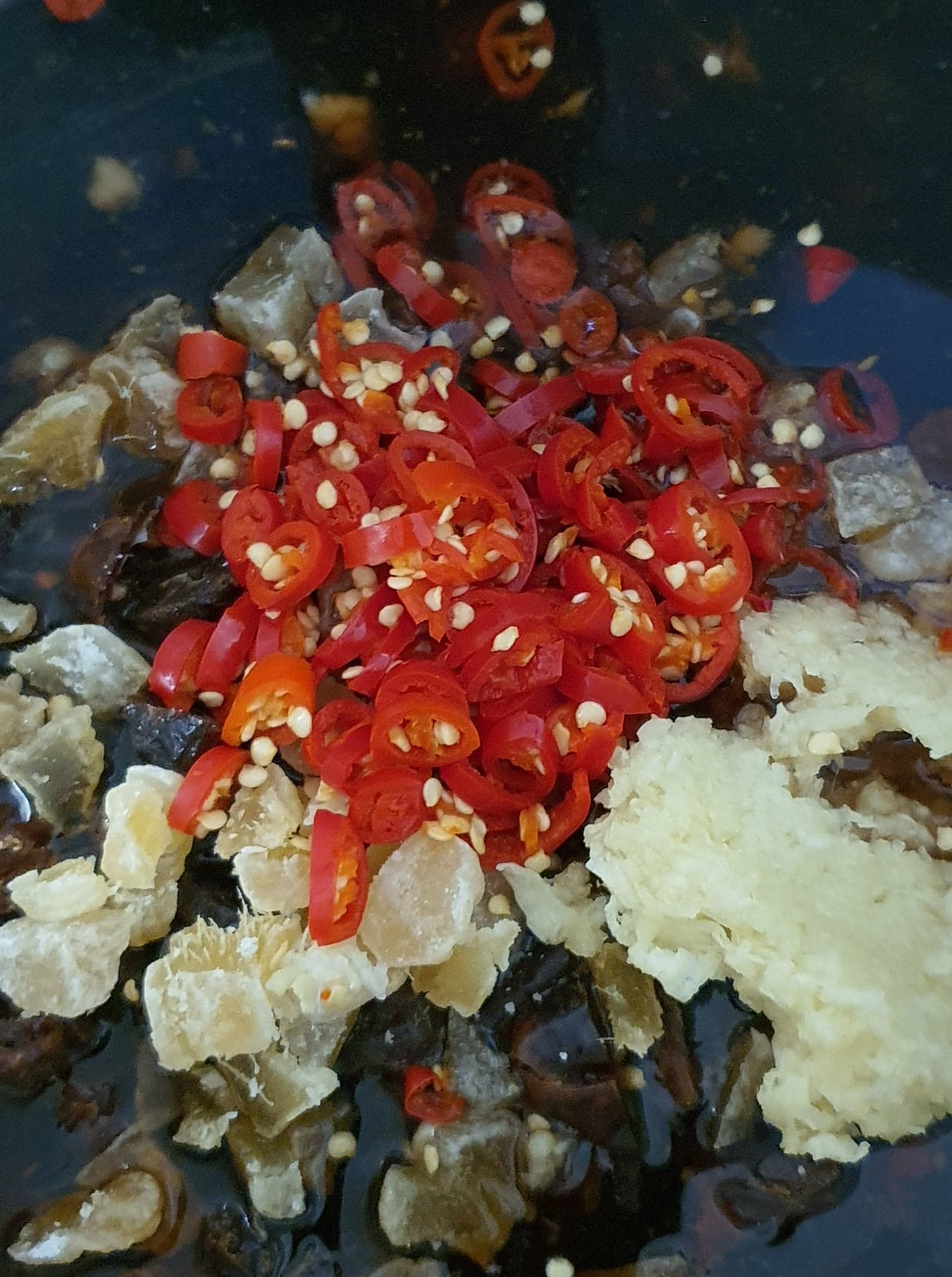 Fresh mangoes, red chillies, ginger, onions, and jars of vinegar and sugar laid out on a bench
